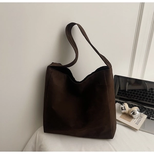 Gros plan d'un grand sac cabas marron en daim mat dans un décor de bureau avec ordinateur
