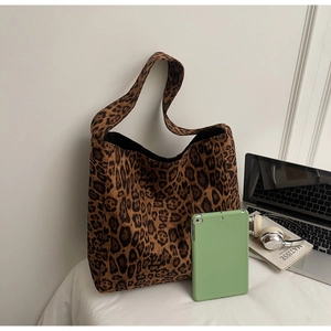 Capacité du sac cabas léopard avec ordinateur et livres sur une surface blanche