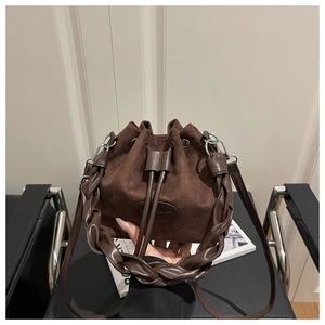 Primo piano di una borsa a secchiello in camoscio marrone scuro con coulisse e manico intrecciato