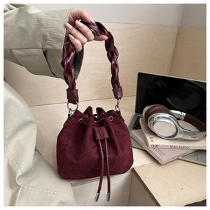 Dettaglio della borsa a secchiello in camoscio bordeaux con manico in pelle intrecciata e coulisse