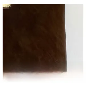 Detail showing high-quality dark brown leather texture with a gold deer pendant charm