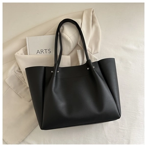 Detail of black faux leather tote bag with silver studs and premium texture finish