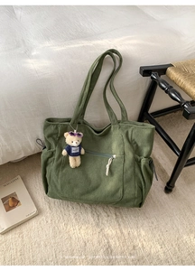 Detail of green corduroy tote bag with zipper pocket and cute bear charm decoration