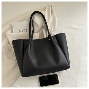 Flat lay of a black matte leather tote bag with rivets, ideal for office commuting