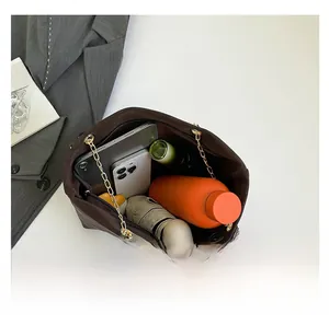 Spacious dark brown tote bag with gold chain showing interior storage for tablet and bottle