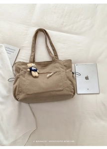 Detail view of khaki corduroy tote bag with large front pocket and cute bear charm decoration