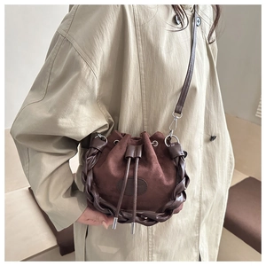 Dettaglio borsa a secchiello marrone scuro in pelle scamosciata con intrecci in pelle