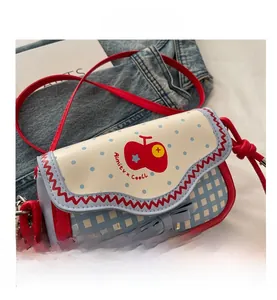 Detail of blue plaid saddle bag with red apple print and white polka dot flap detail