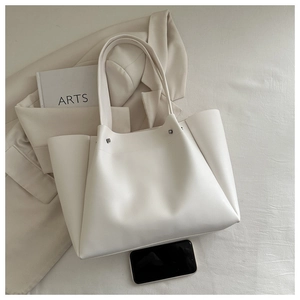 Top view of cream large capacity tote bag on minimalist background with suit jacket