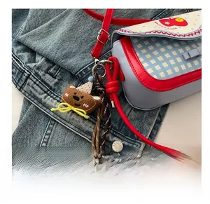 Close-up of cute plush bear charm with polka dot hat on a blue checkered saddle bag