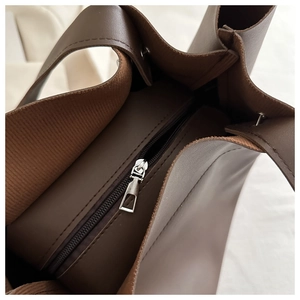 Detail of premium brown leather texture with silver metal zipper on a large tote bag