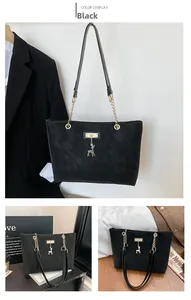 Detail of black tote bag with gold chain strap and deer pendant on a fashion magazine