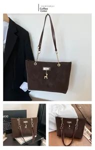 Detail of coffee suede tote bag with deer charm and gold chain shoulder strap