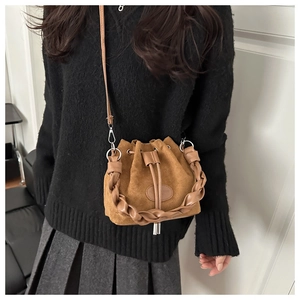 Dettaglio della borsa a secchiello in pelle scamosciata marrone con manico intrecciato