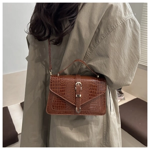 Piccola borsa quadrata marrone motivo coccodrillo con fibbia dorata su modella