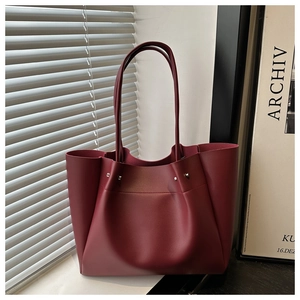 Detail view of burgundy leather tote bag featuring silver studs and slender shoulder straps