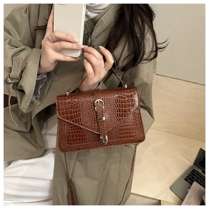 Detail shot of brown crocodile embossed crossbody bag with metallic clasp and top handle