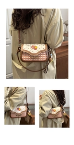 Detail view of plaid crossbody bag featuring red apple print and doll pendant detail