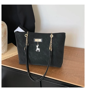 Detail of black matte tote bag featuring gold deer charm and chain leather strap