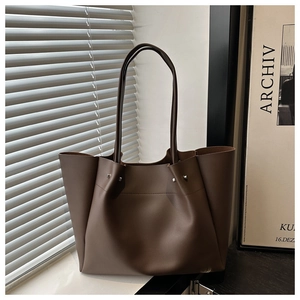 Close-up of deep brown tote bag featuring pleated leather texture and silver rivet details