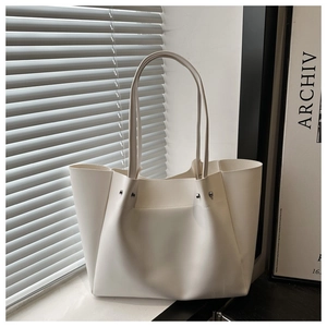 Close-up of white minimalist tote bag with silver studs and smooth leather texture
