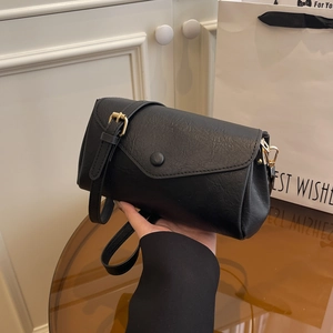 Minimalist black textured shoulder bag with golden hardware and adjustable strap