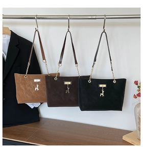Close-up of suede tote bags with gold chain straps and metal deer charms in various colors