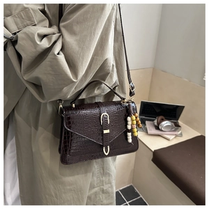 Dettaglio borsa in pelle marrone scuro con trama a coccodrillo e chiusura dorata di lusso
