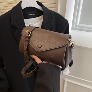 Brown vintage faux leather crossbody bag with wide strap and gold hardware on black background