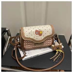 Detail of red apple print and plaid pattern cross-body bag with cute bear charm