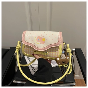 Detail of plaid crossbody bag featuring a pink dotted flap and cute plush bear charm