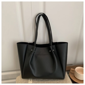 Detail view of black PU leather tote bag with silver metal studs and brand tag