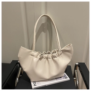 Detail of cream pleated cloud tote bag with soft PU leather texture on a sleek black chair