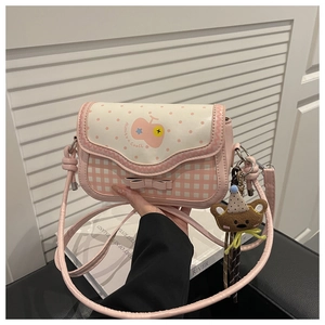 Detail of pink plaid crossbody bag with a cute bear charm and polka dot flap design