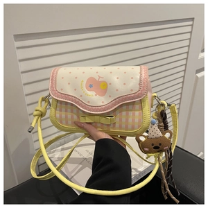 Detail of sweet checkered crossbody bag with pink dots, yellow bow and plush bear charm