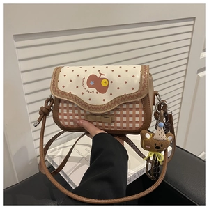 Detail of red apple pattern and plaid design on a Korean-style crossbody bag with bear charm