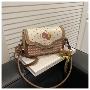 Detail of checkered shoulder bag with fruit pattern and cute bear plush charm on books