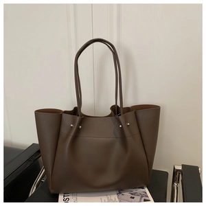 Detail of dark brown tote bag with slim straps and silver metal rivet accents
