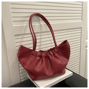 Detail of dark red ruched cloud bag with soft leather texture on book props