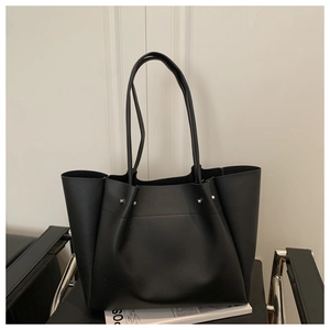 Detail view of black faux leather tote bag with silver studs and thin shoulder straps
