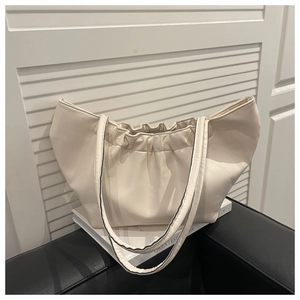Detail of beige pleated cloud handbag showing soft leather texture and stylish bucket shape