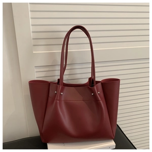 Detail view of burgundy tote bag with silver studs on a white textured background
