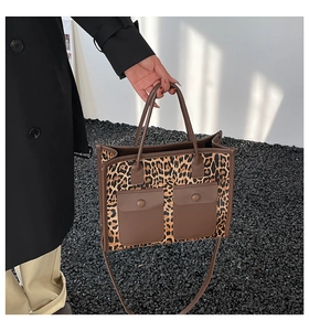 Detail of leopard print tote bag with brown leather handles and two front flap pockets