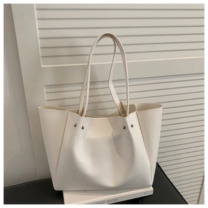 Close-up of cream tote bag with silver studs on books against shutter background