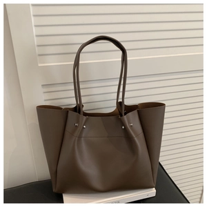 Detail of dark brown tote bag with matte leather finish and silver rivet accents