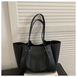 Detail of black matte leather tote bag featuring silver rivets and slim shoulder straps