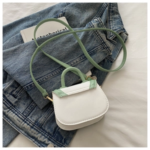 Detail of mini saddle bag in white and mint green on denim background with gold hardware
