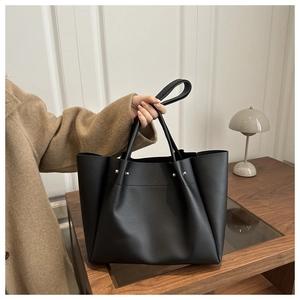 Close-up of black matte leather tote bag with metallic studs and dual handles