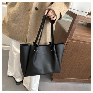 Close-up of black matte leather tote bag with silver rivets and spacious design