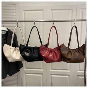 Row of pleated shoulder bags in beige, black, burgundy, and dark brown on hangers